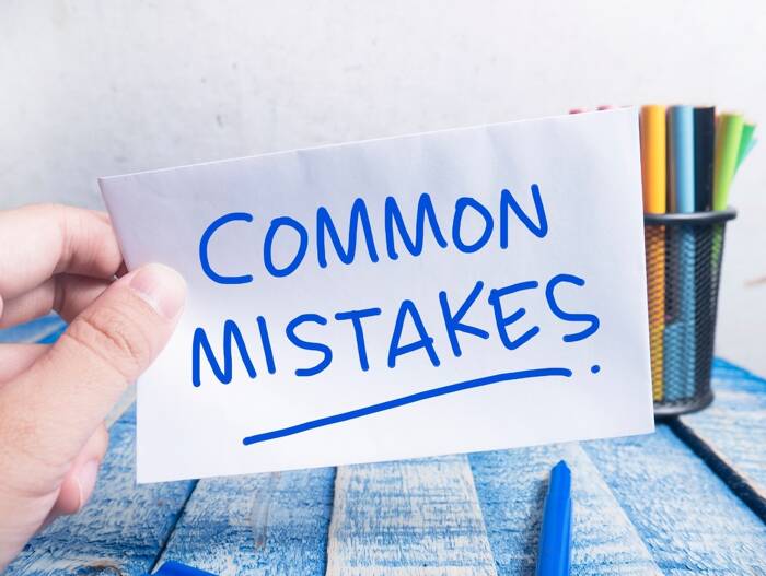 A hand holding a sign with blue text saying 'common mistakes'