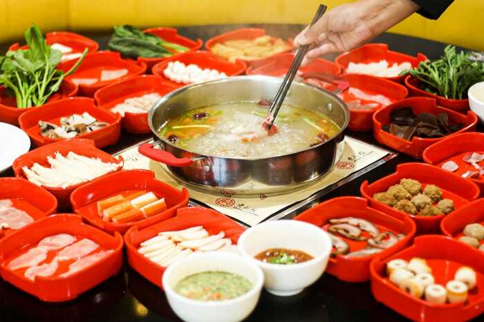 Chinese hot pot with various ingredients around, cooking in a simmering broth