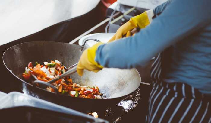 Chef stir-frying colorful vegetables in a traditional wok, demonstrating the chǎo cooking method